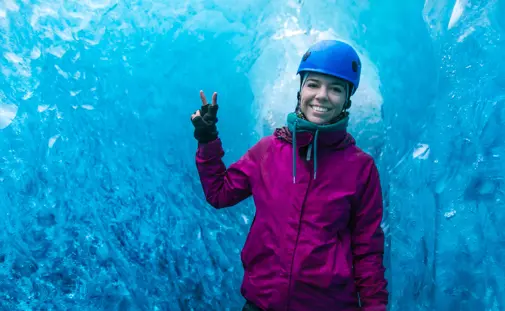 Happy woman inside a glittering blue ice cave during a guided glacier tour in Vatnajökull National Park, Iceland