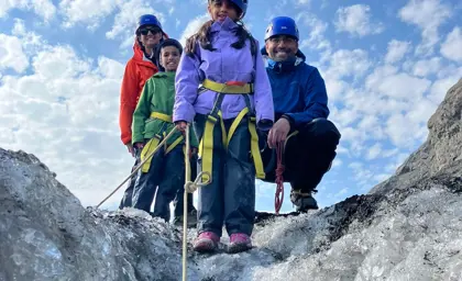 Family dressed in safety gear posing on a glacier during a South Shore Blue Ice Cave Tour in Iceland with Travel Reykjavík.
