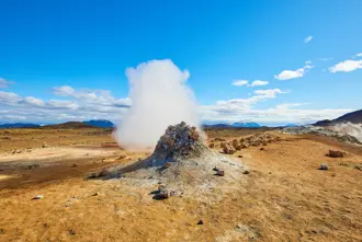 Námaskarð Geothermal Area with steam rising up to a blue clear sky.