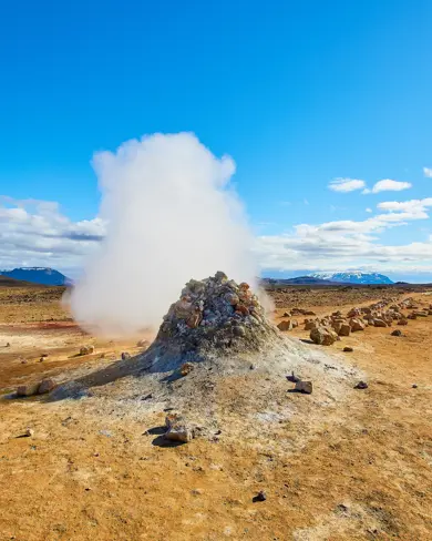 Námaskarð Geothermal Area with steam rising up to a blue clear sky.