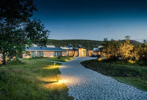 Beautifully illuminated exterior of Hotel Húsafell at dusk, blending seamlessly with Iceland’s natural landscapes.