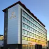 Exterior view of Reykjavík Lights Hotel, a modern multi-story building with a wave-like red roofline and large reflective windows at sunset.