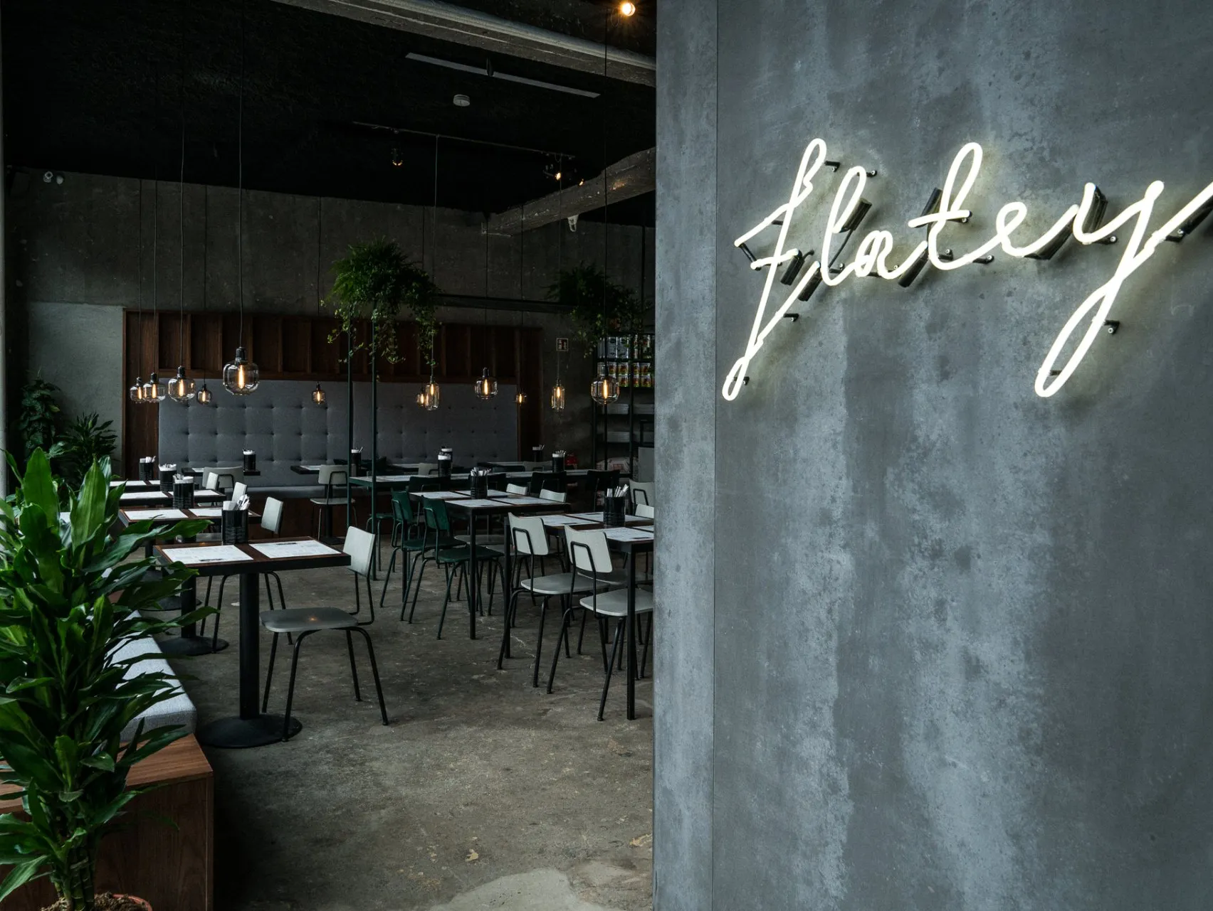 Interior of Flatey Pizza Reykjavík, showcasing modern industrial design with cozy seating and neon signage, a popular spot for authentic wood-fired pizzas in Iceland.