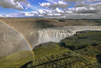 West side of Dettifoss waterfall with rainbow over the waterfall.