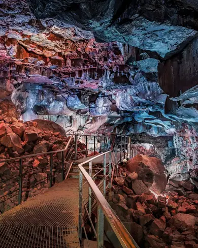 Views inside Raufarhólshellir lava tunnel cave in Iceland with walking path going through the cave.