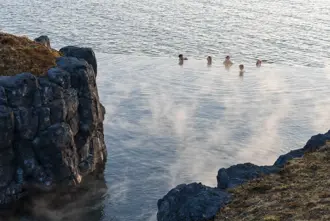 Visitors enjoying the stunning cliffside view from Sky Lagoon's infinity-edge geothermal pool in Reykjavík, Iceland.
