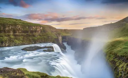 View of the stunning Gullfoss waterfall in Iceland during sunset, with mist rising from the powerful falls.