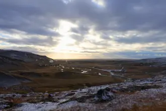 Aerial view of Reykjadalur hot spring valley with snow covered ground and a winter sunset in Iceland.