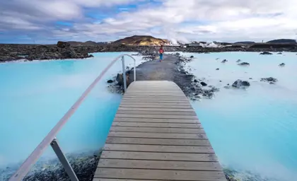 A view of the Blue Lagoon hot spring in Iceland, with turquoise waters and a walkway leading through the geothermal landscape.