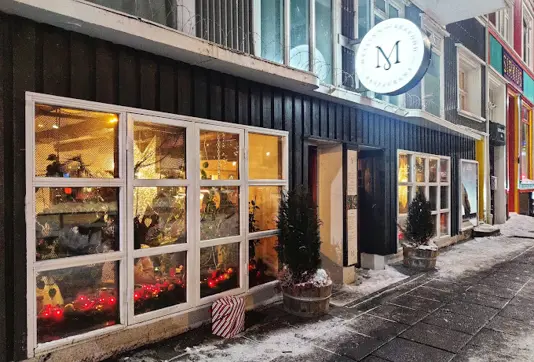 Exterior view of Messinn seafood restaurant in Reykjavik, Iceland, featuring festive decorations, warm interior lighting, and a cozy winter ambiance.