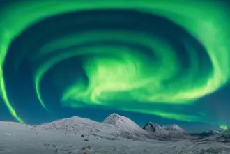 Aurora Borealis Over Snowy Mountains in Iceland.
