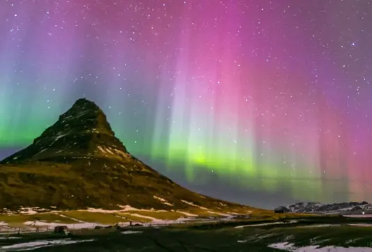 Colorful Aurora Borealis in Pink, Purple, Green, and Blue Over Kirkjufell Mountain in Iceland.