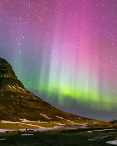 Colorful Aurora Borealis in Pink, Purple, Green, and Blue Over Kirkjufell Mountain in Iceland.