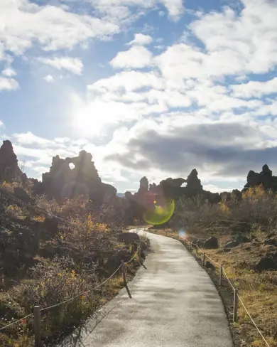 Pathway through lava formations in Dimmuborgir, Mývatn, Iceland, under a bright sky, part of a scenic tour around Iceland with Travel Reykjavik.
