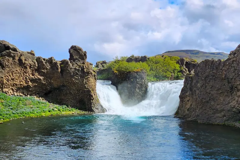 Hjalparfoss waterfall flowing into a lake on a sunny day in Thjorsardal valley in Iceland.
