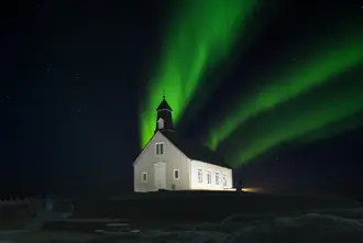 Aurora above old Icelandic church on a dark winter night in Iceland.