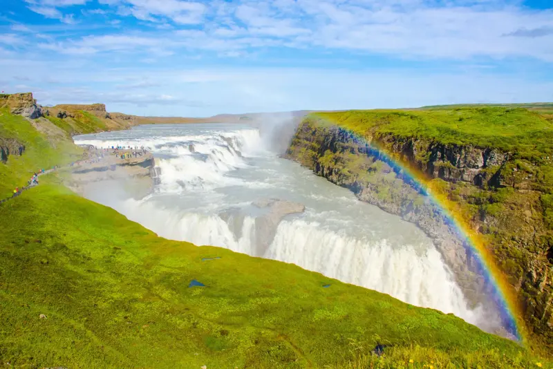 Breathtaking view of Gullfoss Waterfall, showcasing the cascading waters and vibrant rainbow, an essential stop on the Journey Around Iceland tour.