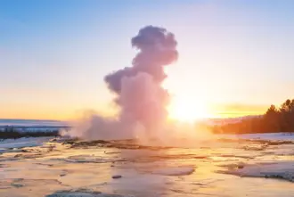 Geysir on the Golden Circle during Northern Light Season in winter covered in snow at sunset.