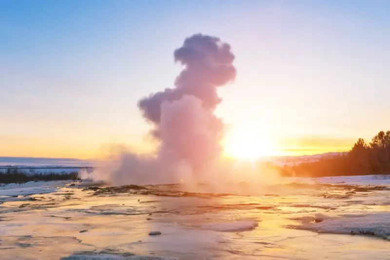 Geysir on the Golden Circle during Northern Light Season in winter covered in snow at sunset.