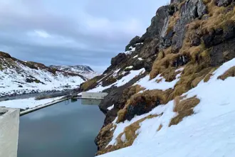 Seljavallalaug Hot Spring Swimming Pool in Winter under a cloudy sky.